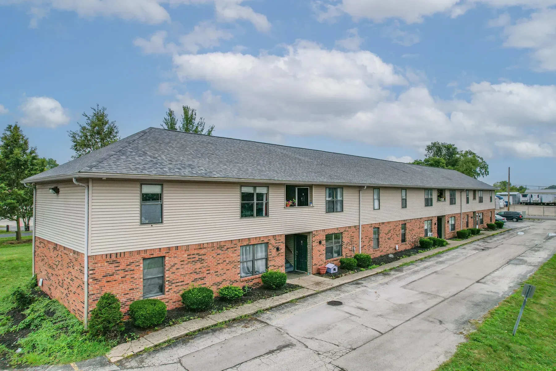 Two-story brick and siding building at Center Place Apartments, Greenfield, beside a paved drive