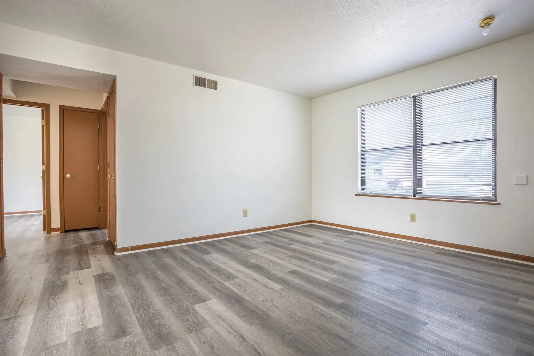 Empty living area with neutral walls and wood-look flooring at Center Place Apartments, Greenfield
