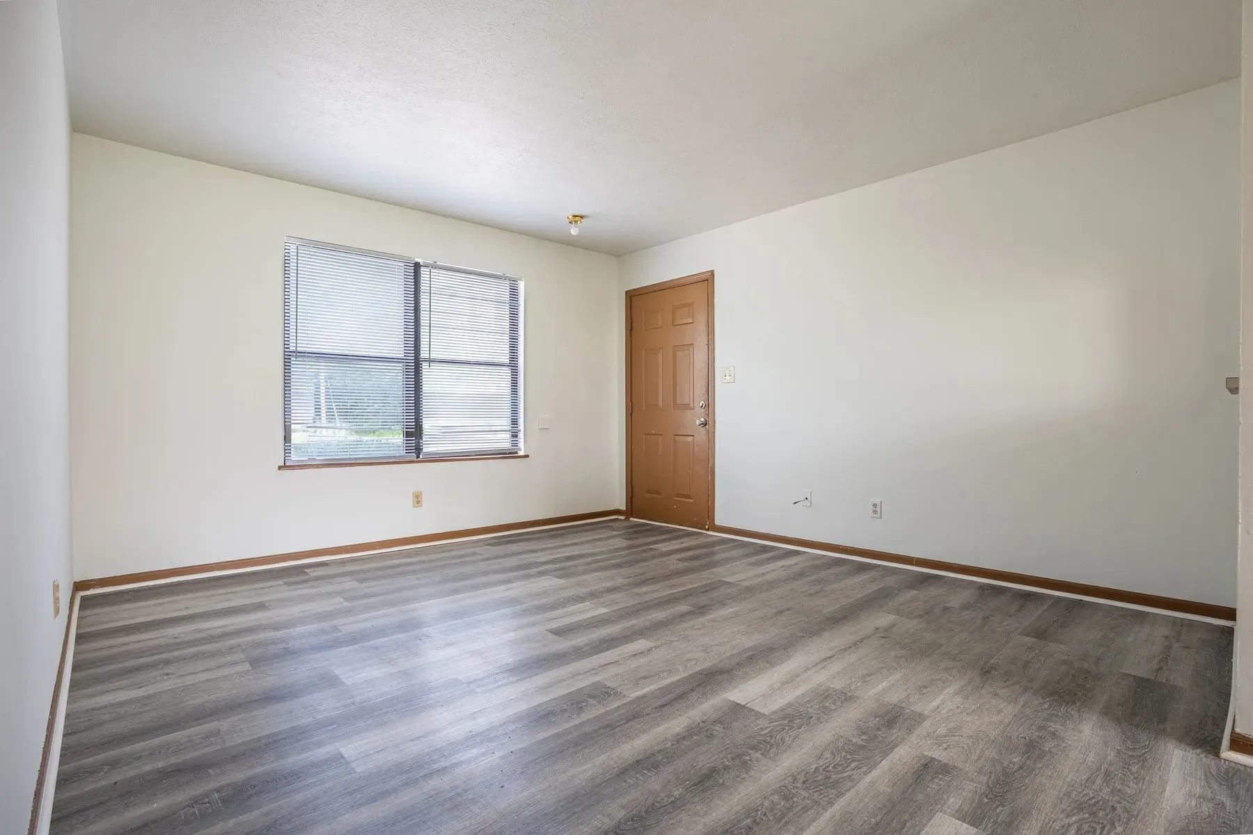 Bright empty room with a window and wide-plank floors at Center Place Apartments, Greenfield