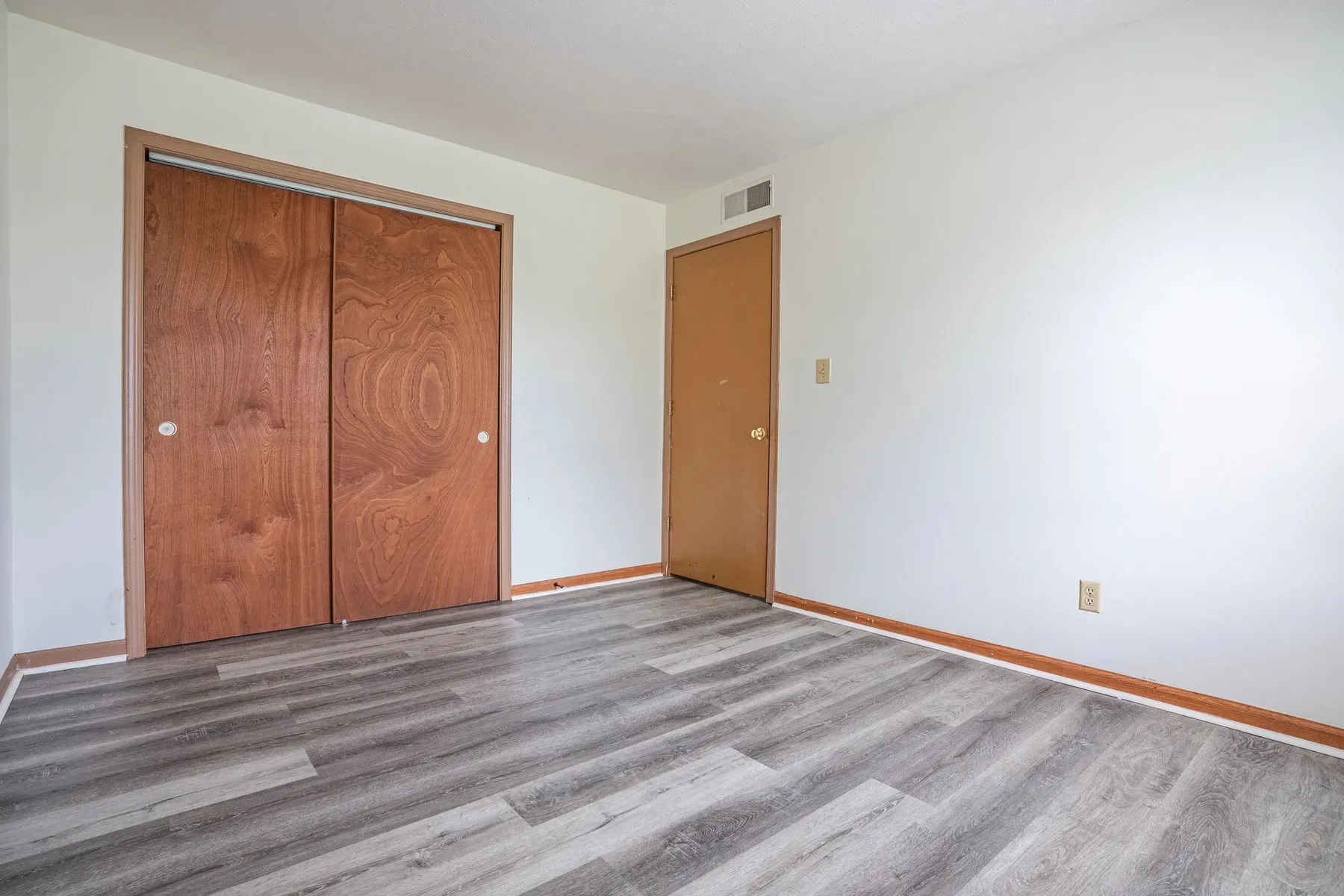 Bedroom with wood closet doors and wood-look flooring at Center Place Apartments, Greenfield