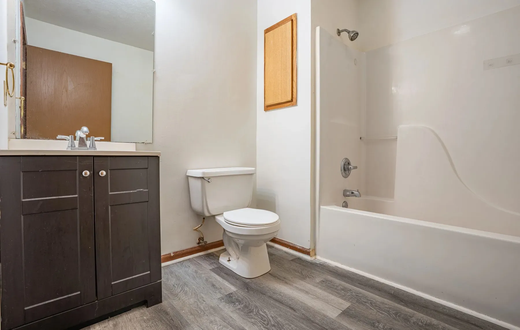 Bathroom with a dark vanity, mirror and shower-tub at Center Place Apartments, Greenfield