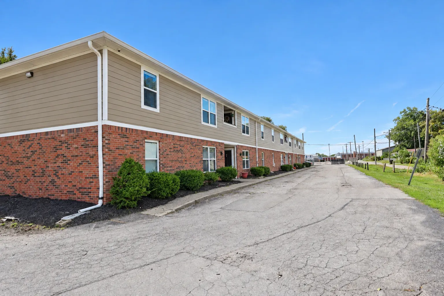 Corner of the Center Place Apartments building, Greenfield, with brick base, shrubs and a long paved drive