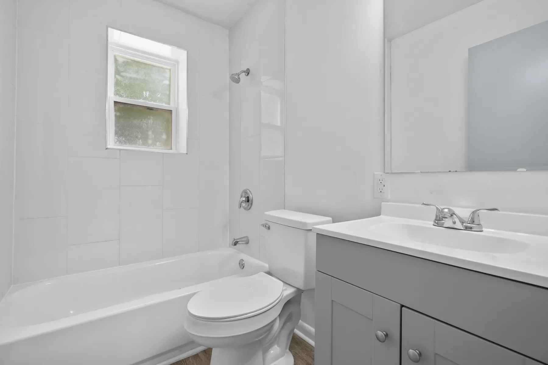 Bathroom with a gray vanity, tub and window