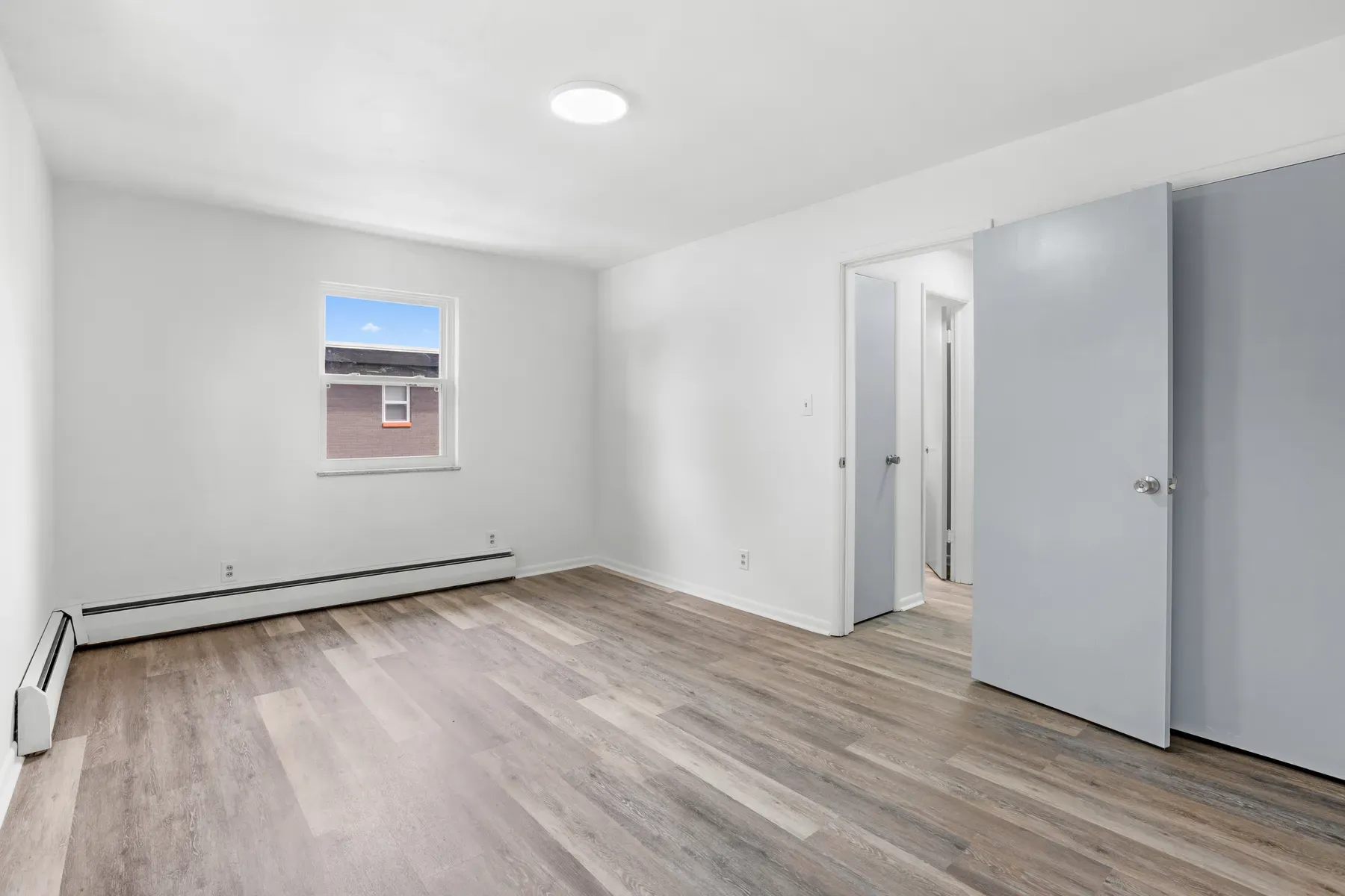 Bedroom with a window, a doorway and gray closet doors