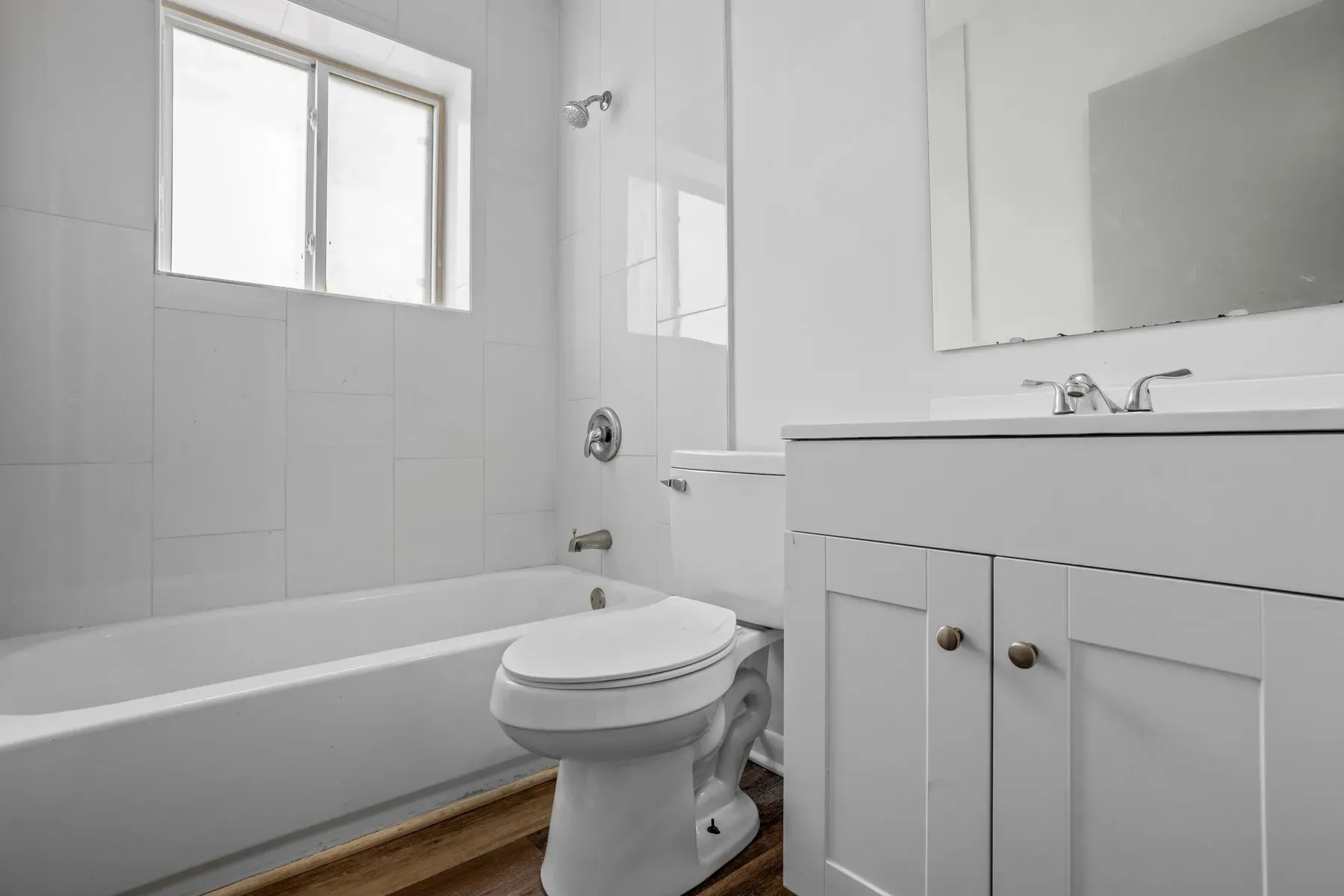 Bathroom with a white vanity, tub and window
