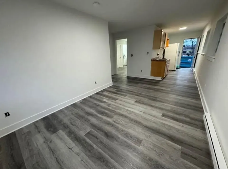 Two-bedroom living area with gray wood-look flooring opening to the kitchen at New Palestine Apartments, New Palestine