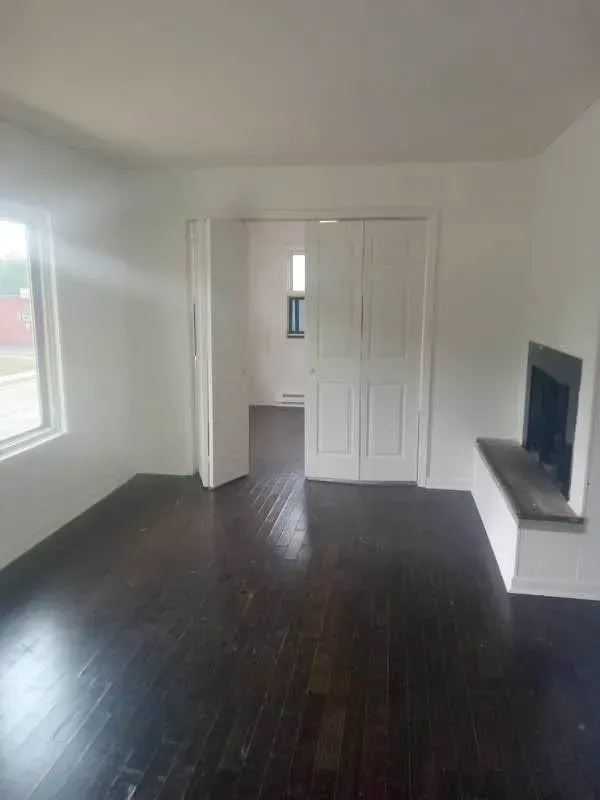 Three-bedroom living room with dark wood floors, white bifold doors and a window at New Palestine Apartments, New Palestine