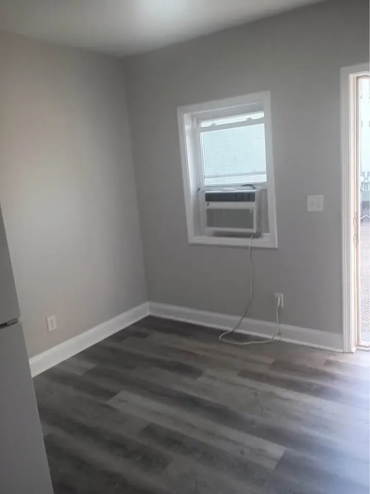 Studio room with gray walls, a window and wood-look flooring at New Palestine Apartments, New Palestine