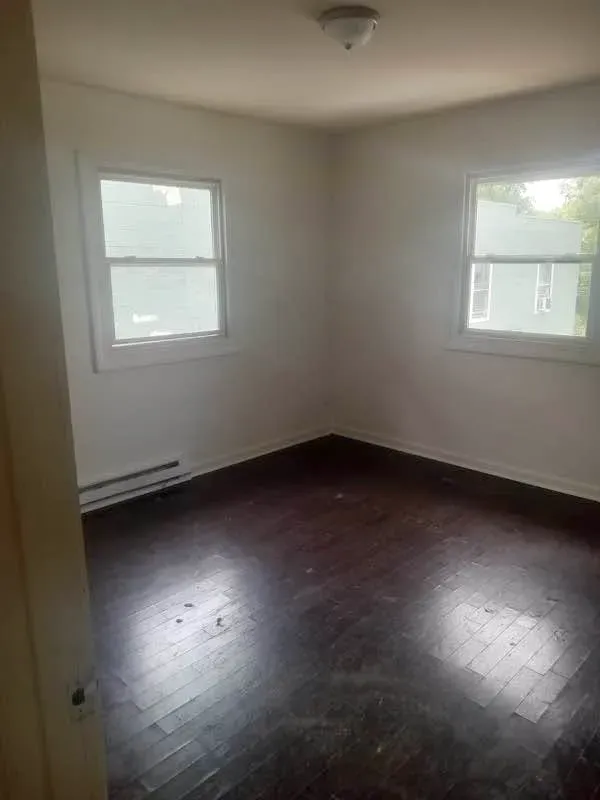 Three-bedroom unit bedroom with two windows and dark wood floors at New Palestine Apartments, New Palestine