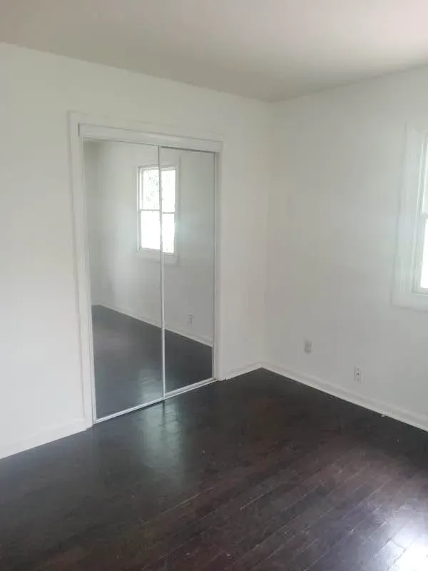 Bedroom with a mirrored closet and dark wood floors at New Palestine Apartments, New Palestine