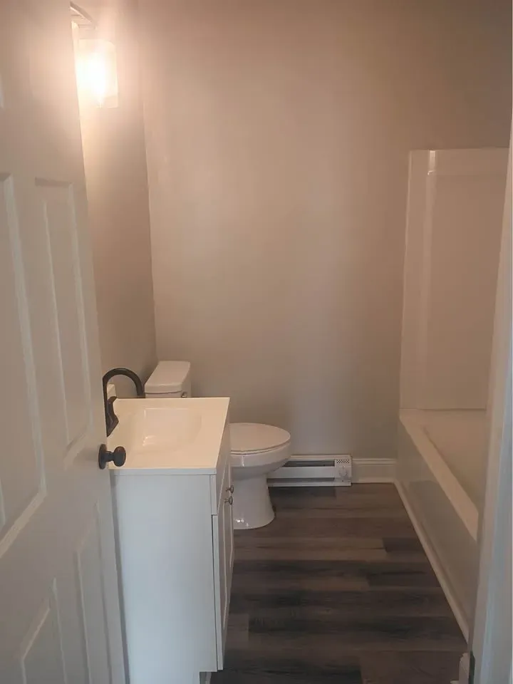 Studio bathroom with a white vanity, toilet and tub at New Palestine Apartments, New Palestine
