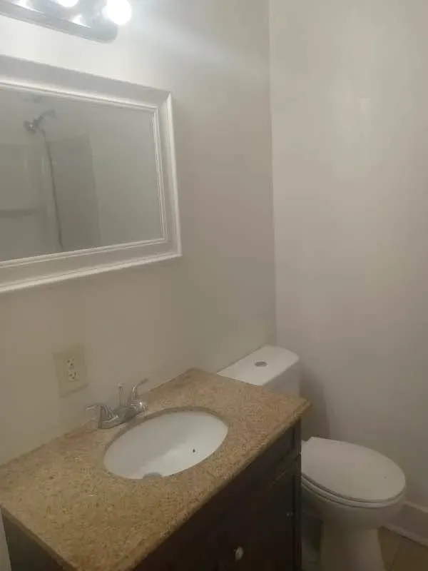 Bathroom with a granite-look vanity, mirror and toilet at New Palestine Apartments, New Palestine