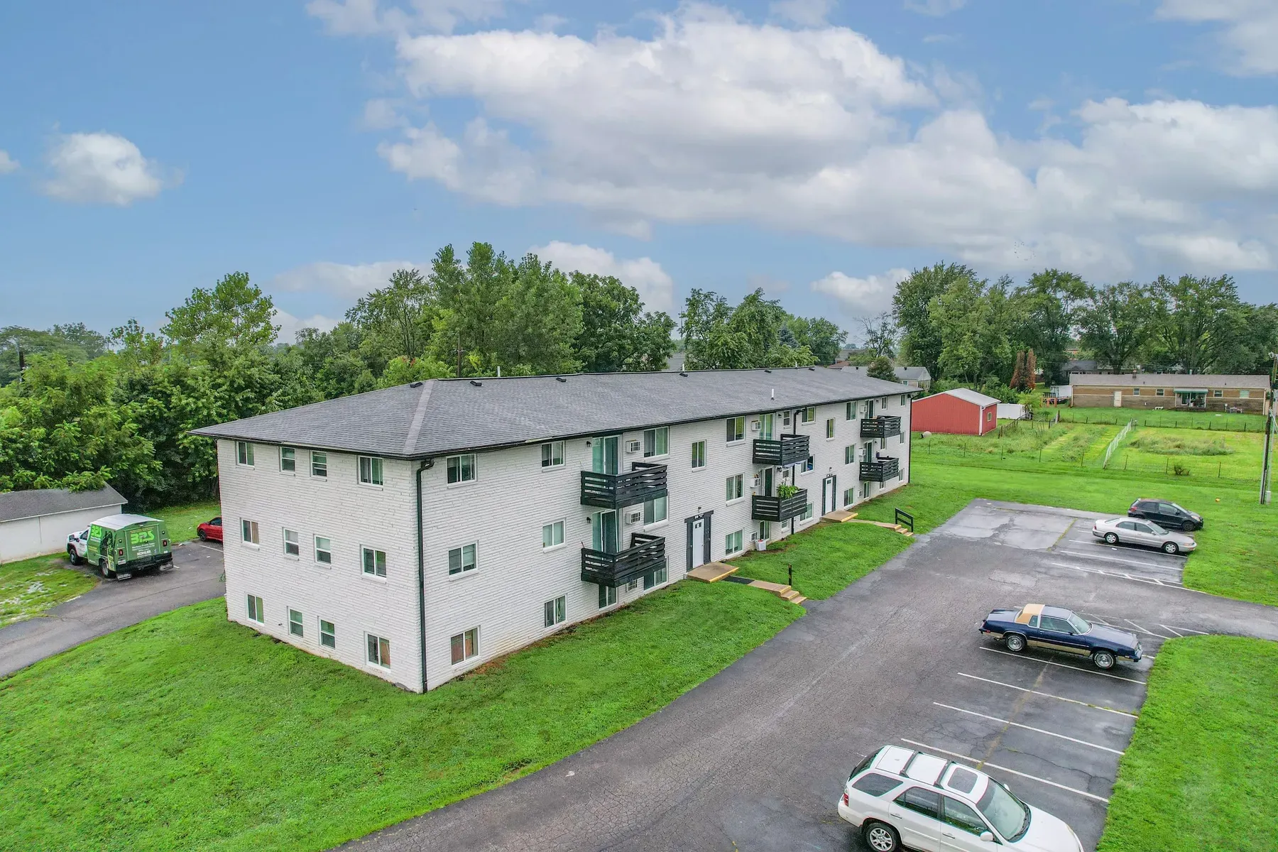 Three-story apartment building with balconies and a parking lot