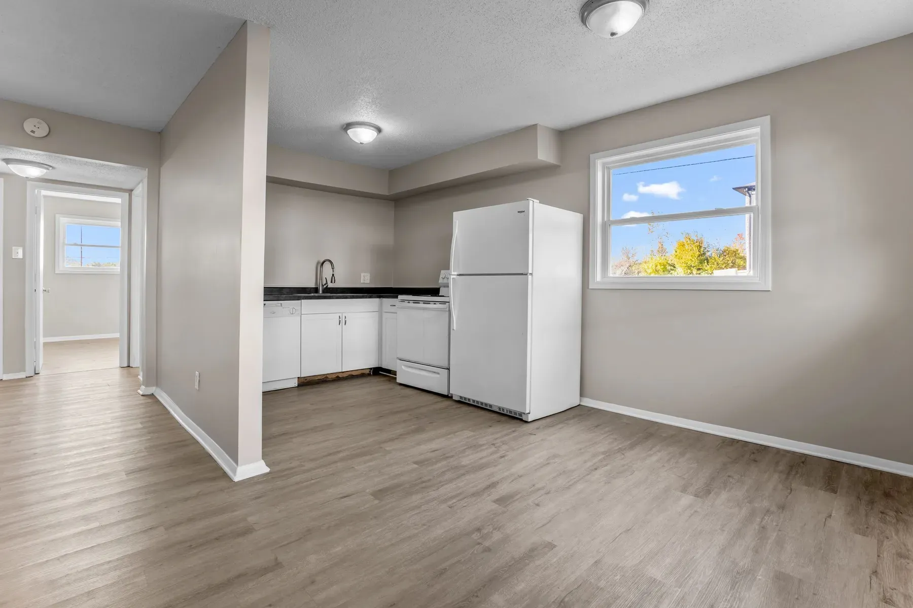 Kitchen with white appliances and a window beside the living area