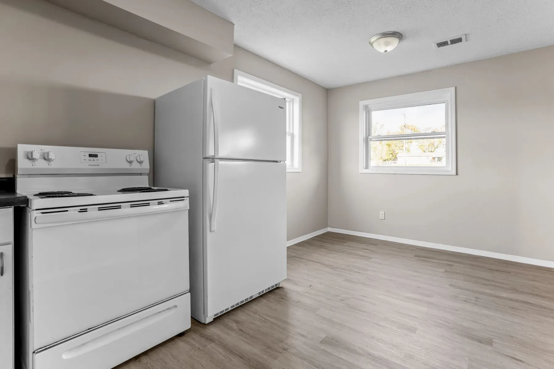 Kitchen with a white range and refrigerator beside a window